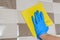 Housemaid in protective gloves washes ceramic tile on the wall with a yellow rag