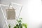 Houseplant and eco bag on rack near white wall.