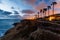 Houses framed by palms lit up at sunset on oceanside cliffs