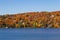 Houses nestled in colourful fall foliage on the side of a mountain overlooking a lake