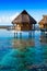 Houses over the transparent quiet sea water. Tahiti