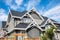 Houses with shingle roof against blue sky. Edge of roof shingles on top of the houses dark asphalt tiles on the roof