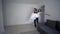 Housewarming, joyful groom carries fiancee on hands in white dress and turns at new house