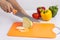 Housewife cutting cabbage with knife on plastic cutting board