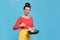 Housewife with frying pan and spatula on blue background