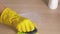 Housewife hand in rubber glove wipes dirty table with cleaning powder with brush
