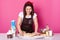 Housewife happily kneads dough with rolling pin. Young dark haired baker dressed in casual t shirt and apron, dirty with flour,