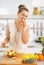 Housewife having a bite while making fruit salad in kitchen