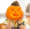 Housewife holding a big Jack-O-Lantern pumpkin in front of head