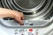 A housewife holds a lint trap from a front-loading tumble dryer. Woman`s hand