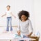 Housewife ironing laundry while girl jumps on bed