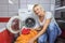 The housewife is kneeling at a pile of dirty laundry