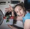 Housewife next to the washing machine looks upset at the defective washing gel, stuck together in a lump, photo from the series