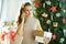 Housewife with parcels using cell phone near Christmas tree