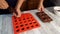 A housewife pours liquid chocolate into a candy mold. The man lays out in the form of cherries in cognac. Homemade chocolates with