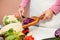 Housewife slicing red cabbage on slices with a knife in the kitchen