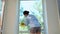 Housewife spraying glass cleanser detergent and using a yellow rag, removes stains and streaks on the panoramic windows