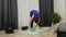 Housewife stretches hamstring muscles at home in bright room. Girl in sportswear pantone blue color doing stretching exercises on