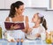 Housewife teaching daughter to prepare omelette and smiling