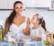 Housewife teaching daughter to prepare omelette and smiling