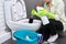 Housewife washing and disinfecting toilet, in gloves with detergent and brush