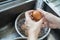 Housewife washing a raw eggs.