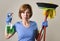 housewife in washing rubber gloves carrying cleaning spray bottle broom and mop