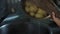 A housewife woman drains water from a pot from a boiled potato into the sink