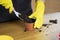 Housewife in yellow rubber gloves pours soil into a planting pot.