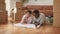 Housing concept. African american spouses lying on floor at new home with paper plan and discussing interior design