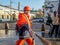 A housing worker in a protective medical mask and in an orange uniform walks along a city street during the day