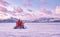 Hovercraft quickly glides over the surface of the transparent frozen Lake Baikal at sunset, winter pink landscape.