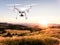 Hovering drone taking pictures of green nature at sunset