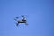 Hovering electronic drone against clear cerulean sky