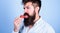 That is how tastes summer. Man handsome hipster with long beard licking strawberry tongue. Hipster enjoy juicy ripe