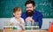 How to interest children study. Fascinating chemistry lesson. Man bearded teacher and pupil with test tubes in classroom