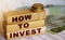 How to invest words written on wooden blocks, 100 Euro banknotes and Euro cents. Investment business concept