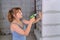 How to repair a new apartment yourself A young woman builder twists a screw into the wall with a screwdriver. Repair of the