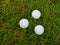 Hree white ping pong balls on a background of green grass close-up, selective focus