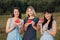 Hree young attractive women friends in blue dresses at sunset are eating watermelon and smiling.