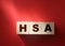 HSA abbreviation on wooden cubes on red. Concept. Health Savings Account