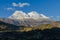 Huascaran mountain in Peru with its two snowy peaks rising over green valley where the town of Yungay sits,