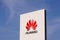 Huawei logotype on white panel sign by headquarters with clear blue sky