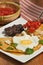 Huevos rancheros meal with a spoon of chopped tomatoes