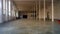 Huge abandoned empty industrial hangar, with white walls and columns.
