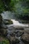 Huge active waterfall in green tropical mountain forest with people watching its flow, Bali. Hidden waterfall. Waterfall landscape