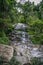 Huge active waterfall in green tropical mountain forest with people watching its flow, Bali. Hidden waterfall. Waterfall landscape