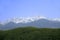 Huge alpine snow-covered ridge with Talgar peak with mountain ranges and green hills at the foot in summer, sunny