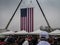 Huge American Flag hangs by cranes as people enter Trump Rally on a cold and rainy day