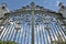 A huge ancient gothic style iron wrought double swinging gate against a deep blue sky backdrop